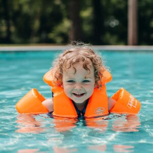 A young child confidently learning to swim with the support and buoyancy of a comfortable children's life jacket.