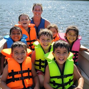 Children happily wearing their bright-colored life jackets while enjoying a boat ride with adult supervision.