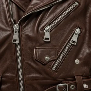 Detailed shot of the sturdy silver hardware and zippers on a brown leather moto jacket.