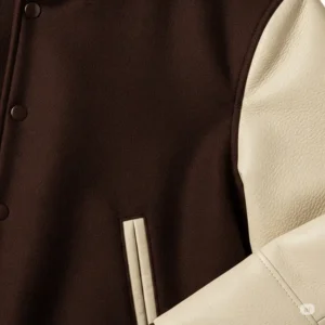 Close-up of the rich brown wool and contrasting cream leather sleeves of a high-quality varsity jacket