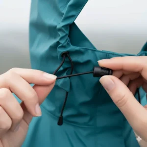 Close-up of the adjustable drawstring toggles on the hood of a women's waterproof packable rain jacket.