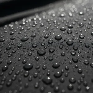 Close-up of water droplets beading on the moisture-wicking fabric of a women's black rain jacket.