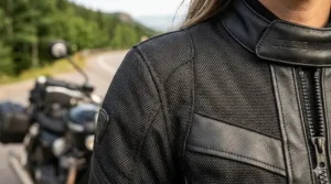 4K photorealistic close-up of a women's armored motorcycle jacket, showing the complex weave of abrasion-resistant Cordura fabric and matte leather.
