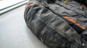 Close-up illustration of reinforced Cordura stitching on an enduro riding jacket for maximum abrasion resistance.