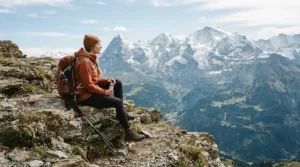 An outdoor enthusiast resting on a Rocky Mountain hiking trail, bundled up in the best down puffer jacket for cold weather warmth.