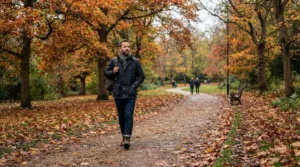 Autumn styling featuring a distressed denim jacket men outerwear option paired with a hoodie in the park.