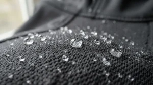 A close-up view of advanced fabric technology on a mens windbreaker jacket shedding raindrops